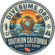 Circular vintage badge logo for Divebums.org. The center illustrates a classic brass diving helmet resting in ocean waves and kelp, backed by a sunset, palm trees, and a rocky shoreline. The outer ring features a nautical rope border with 'DIVEBUMS.ORG' at the top and 'SOUTHERN CALIFORNIA SCUBA SITE GUIDE' at the bottom, accented by small scuba gear icons and a dive flag.