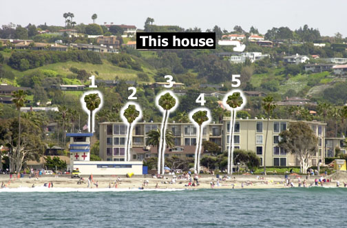 Boxy white house on hill with palm trees by the lifeguard tower